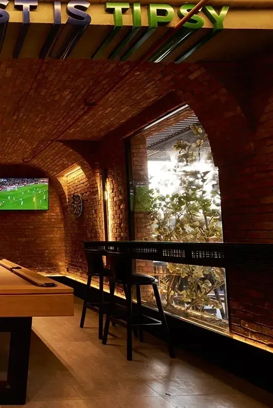 Brick arch window with a football screen and a high table