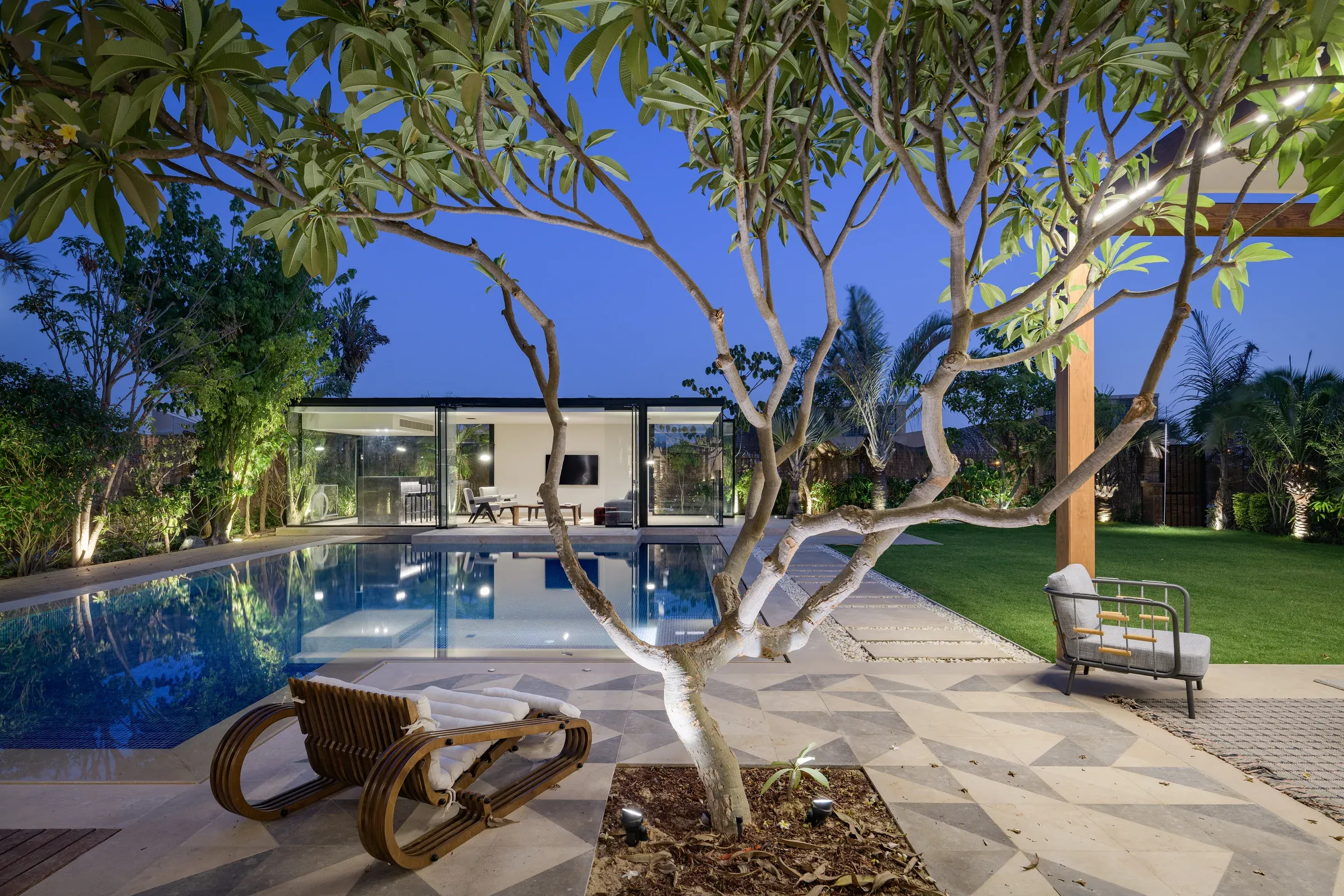 Frangipani tree beside the pool with a wooden lounger at dusk