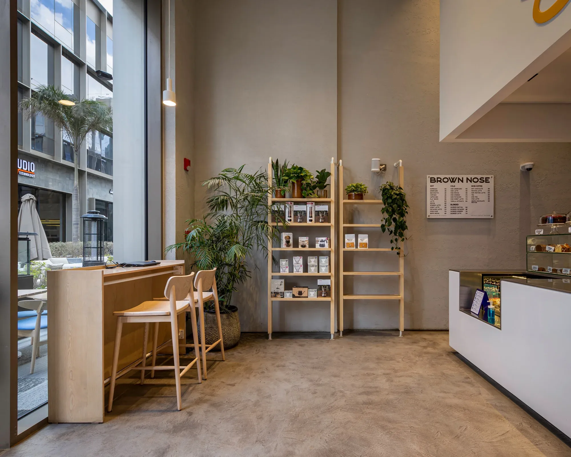 Timber shelving with plants and coffee bags beside the white counter