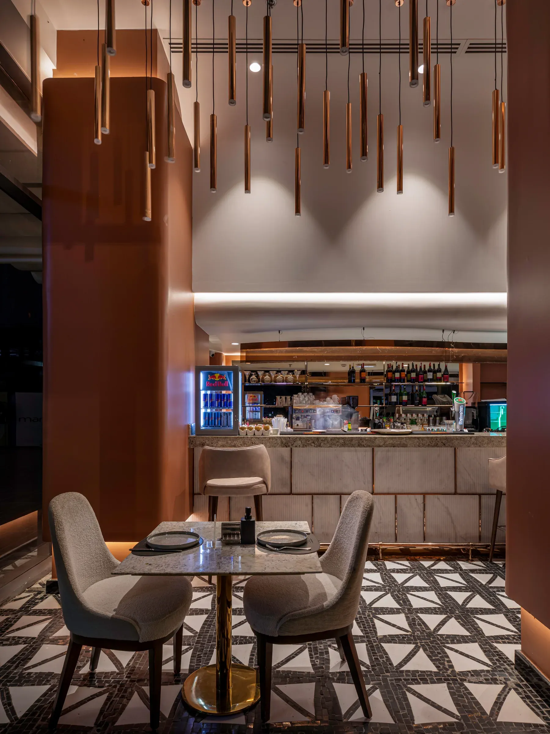 Two-seat table in front of the bar beside a lit terracotta column