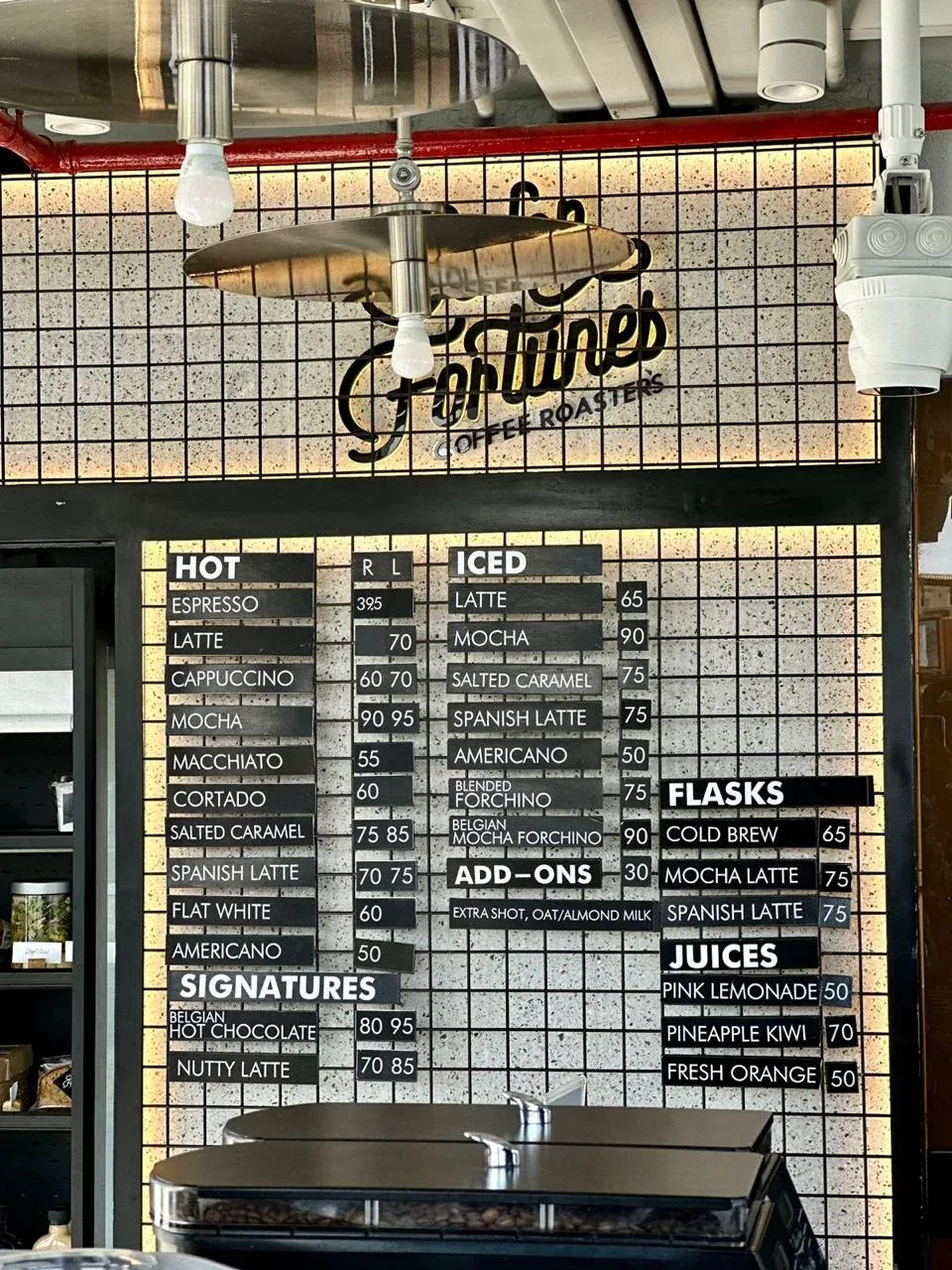 Drink menu board on a black mesh panel under the logo