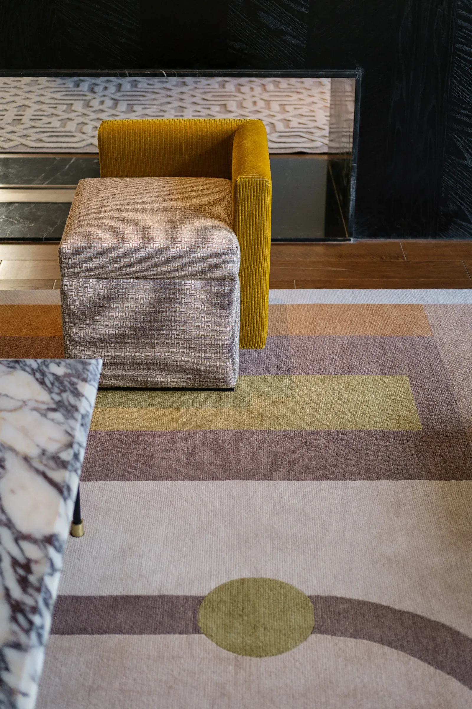 Pastel geometric rug beside a marble table and a yellow chair