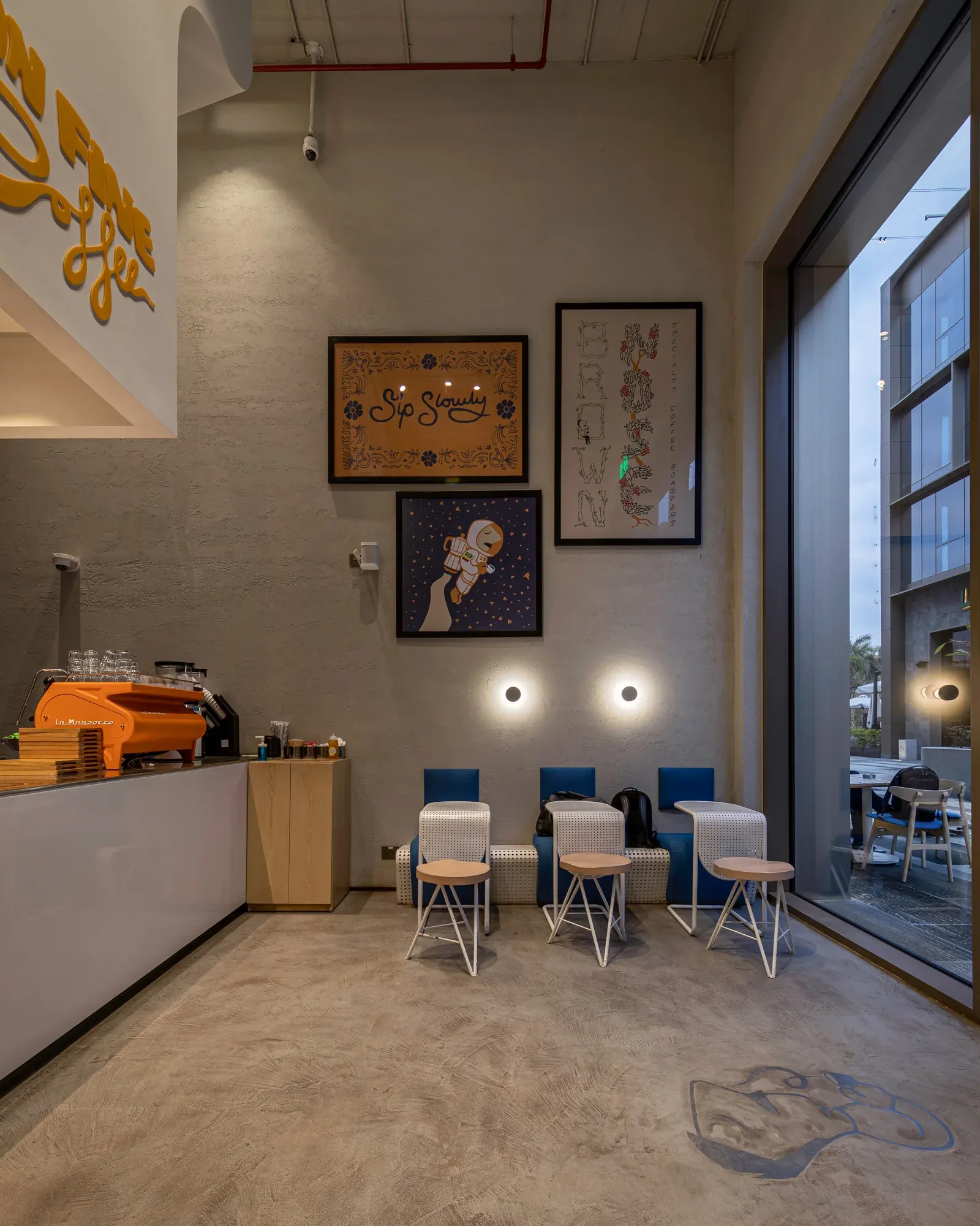 White counter with orange espresso machine and framed art above