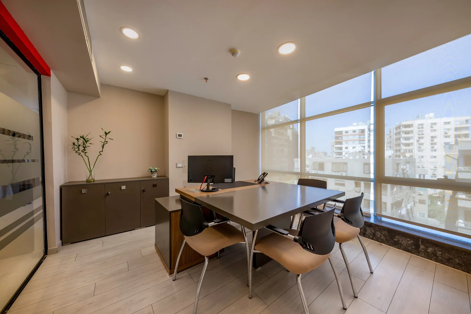 Meeting room with timber table, tan chairs and a window onto the city