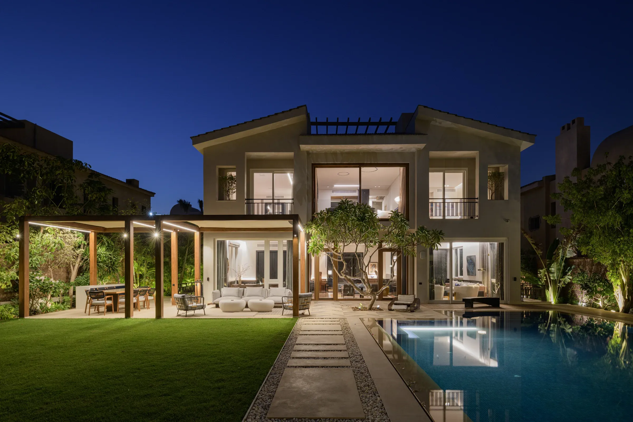 Rear of the villa at night with lawn and lit pool
