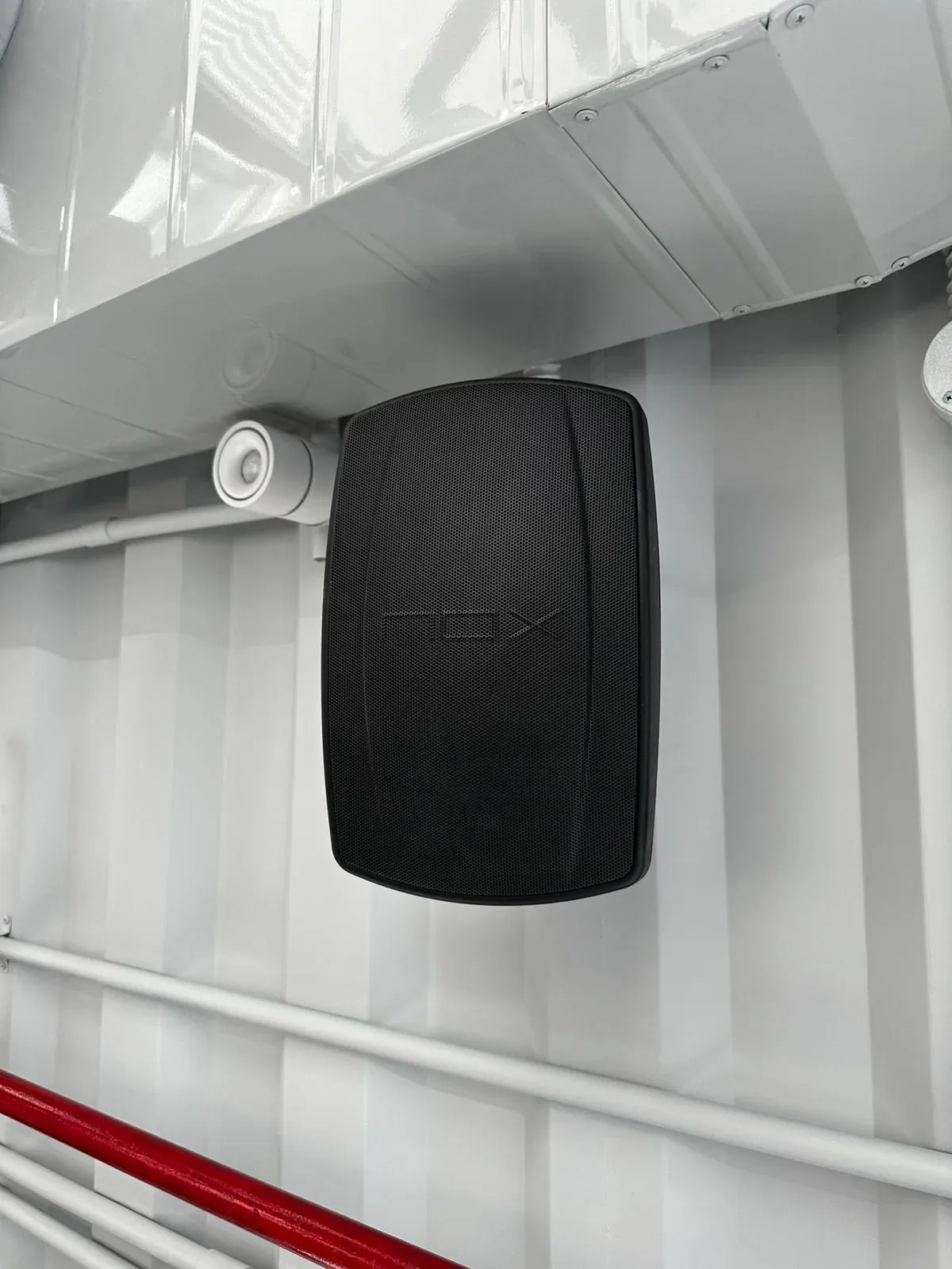 Black speaker mounted on a white wall with red trim